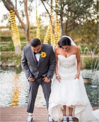 a bride and groom standing next to a pond